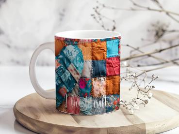 Weißer Keramikbecher mit einem farbenfrohen Patchwork-Design, das ein Herzmotiv zeigt. Der Becher ist mit Stoffmustern in Blau-, Rot-, und Orangetönen bedruckt, und der Text 'love to craft' ist in einer weißen, geschwungenen Schrift am unteren Rand sichtb